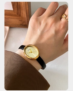 Close-up of GEDI vintage oval women's watch with golden case and black leather strap
