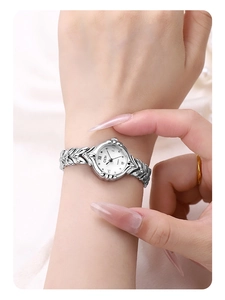 Detail of silver wheat-ear chain strap and white dial on an elegant lady quartz watch