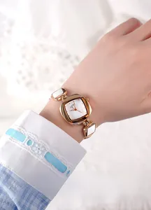 Close-up of a women's rose gold quartz watch with a white inlaid link bracelet on wrist