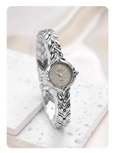 Macro shot of silver wheat link bracelet watch with date window on a textured stone
