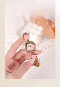 Close-up of elegant rose gold irregular quartz watch with pink stone bracelet inserts