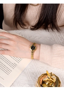 Dettaglio di un elegante orologio a catena dorata da donna con quadrante nero e diamanti