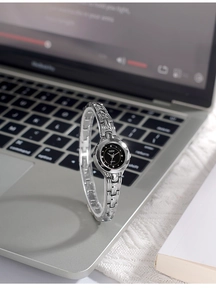 Orologio a bracciale in lega argento lucido con quadrante nero su una scrivania moderna