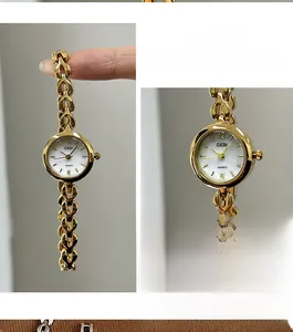 Makroansicht der zierlichen goldenen Kettenuhr mit weißem Perlmuttzifferblatt und Metallarmband
