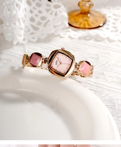 Detailed shot of a rose gold quartz watch with pink mop dial on white lace cloth