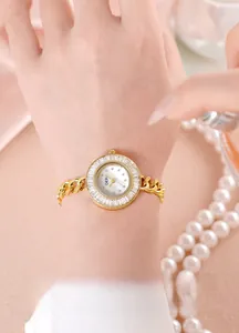 Close-up of luxury gold-tone watch with zircon bezel and pearl necklace accessories