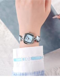 Close-up of GEDI silver watch with light blue dial on a wrist with lace background
