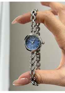 Detail von silbernem herzförmigem Kettenarmband und blauem Zifferblatt der Damenuhr