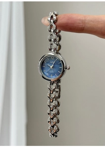 Detail einer silbernen Kettenuhr mit blauem Zifferblatt und herzförmigen Gliedern