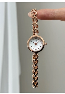 Details des roségoldenen herzförmigen Kettenarmbands und weißen Zifferblatts der Damenuhr
