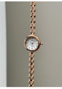 Detail einer roségoldenen Quarzuhr mit herzförmigem Gliederkettenarmband und Perlmutt-Zifferblatt