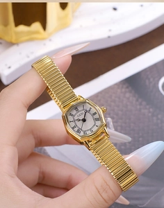 Detail of gold tonneau watch featuring a Roman numeral dial and flexible snake chain strap
