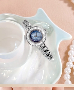 Close-up of a luxury silver quartz watch with baguette-cut zircons and a navy blue dial