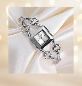 Detail shot of a silver square watch dial on white silk with elegant chain strap
