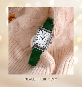 Close-up of retro square ladies watch with green leather strap on soft pink sweater