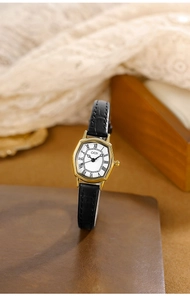 Dettaglio dell'orologio tonneau dorato vintage con numeri romani e pelle nera