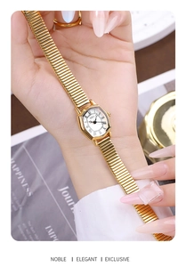 Detail of GEDI gold barrel watch with roman numerals and elastic metal band held by hand