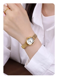 Close-up of vintage octagonal gold watch with Roman numerals and stretch band on wrist