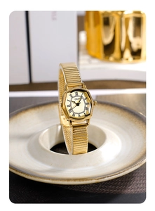Macro shot of gold tonneau watch dial with Roman numerals and serpent strap on ceramic plate