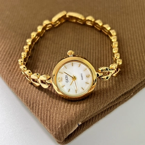 Elegante goldene Damen-Quarzuhr mit kleinem Zifferblatt und Kettenarmband auf braunem Stoff
