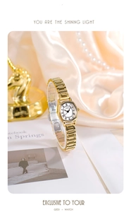 Detail of tonneau-shaped gold watch on silk with elegant Roman numeral dial display