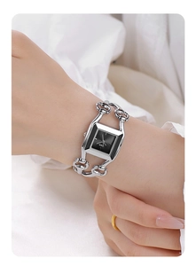 Close-up of GEDI square black dial watch with silver hollow chain bracelet on a wrist
