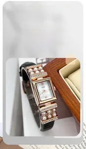 Détail d'une montre à quartz carrée de luxe avec perles et bracelet en cuir noir