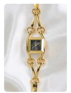 Detail of square black dial and golden bracelet watch on white satin fabric background