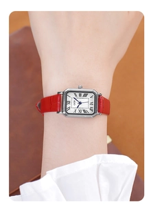 Classic rectangular silver watch with red leather strap and Roman numeral dial on a wrist