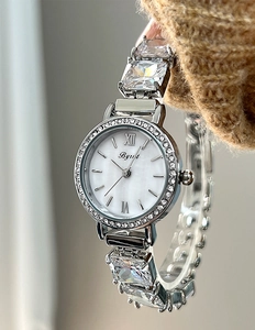 Macro detail of mother-of-pearl watch face with zircon bracelet on a knit sleeve