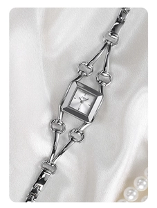 Detail of silver square watch dial on silk background with pearl necklace decoration