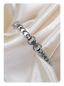 Macro shot of silver polished rectangular link bracelet on smooth ivory silk fabric