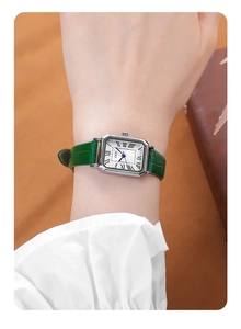 Close-up of rectangular silver watch with green leather strap and Roman numerals