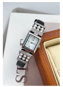Détail d'une montre argentée rectangulaire avec perles et bracelet en cuir noir