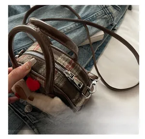 Detail of checkered tweed kids handbag with plush heart charm and glossy brown leather strap
