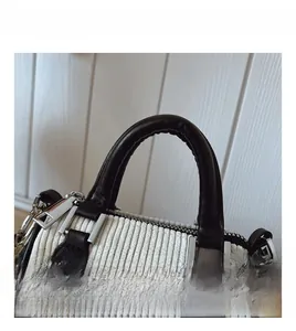 Détail du sac seau en velours côtelé rayé avec poignée en cuir noir et métal