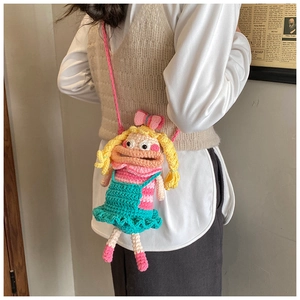 Detail of handcrafted crochet cartoon girl crossbody bag with yellow hair and green dress
