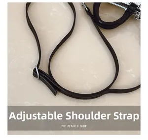 Détail de la bandoulière réglable sur le sac seau en cuir noir avec boucle métallique argentée