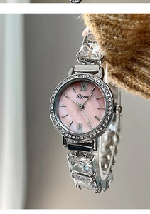 Macro detail of silver watch with pink mother-of-pearl dial and crystal bracelet