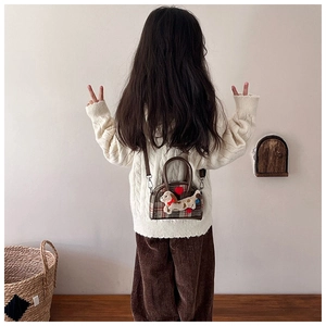 Detail of red plaid kids handbag featuring a cute plush dachshund and brown leather handle
