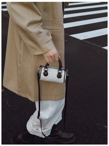Détail d'un sac tonneau enfant en velours côtelé rayé avec anses et bandoulière en cuir noir