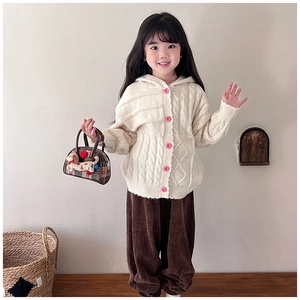 Detail of child wearing cream knit cardigan with pink buttons and a checkered puppy handbag