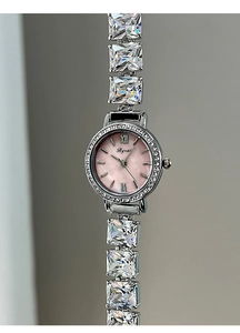 Macro detail of silver watch with pink mother of pearl dial and square crystal bracelet