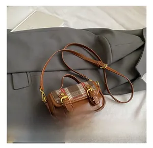 Close-up of vintage brown leather bag with plaid wool flap and gold buckles