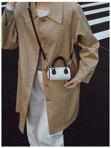 Vue détaillée du mini sac seau en velours côtelé beige porté en bandoulière avec trench