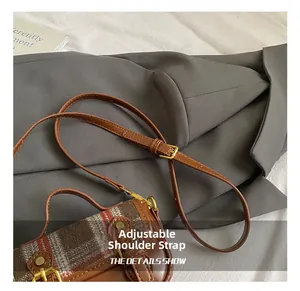 Detail of adjustable leather shoulder strap with gold buckle on vintage plaid bag