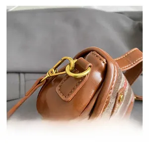 Close-up of golden swivel hook and leather stitching on vintage plaid girl's shoulder bag