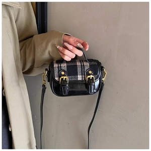 Detail of vintage tweed plaid crossbody bag featuring double gold metal buckles and leather trim