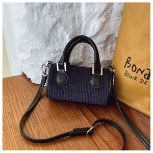 Détail du sac seau en velours côtelé bleu marine avec poignée en cuir noir et garniture argent
