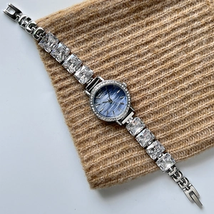 Silver bracelet watch with square zircons and deep blue textured dial on knit background